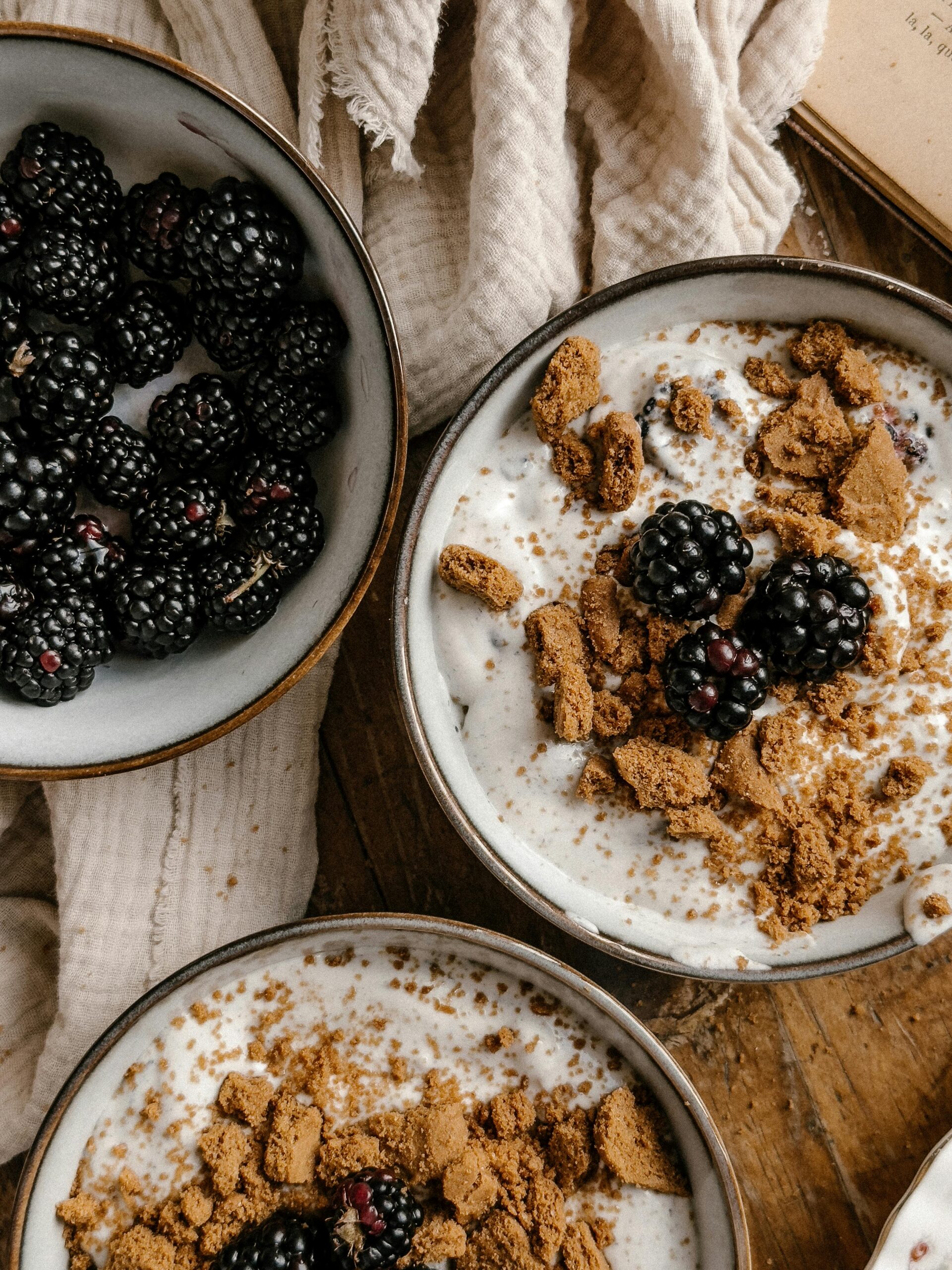 Overhead view of multiple bowls of homemade cream of wheat with berries and brown sugar on a rustic kitchen surface.