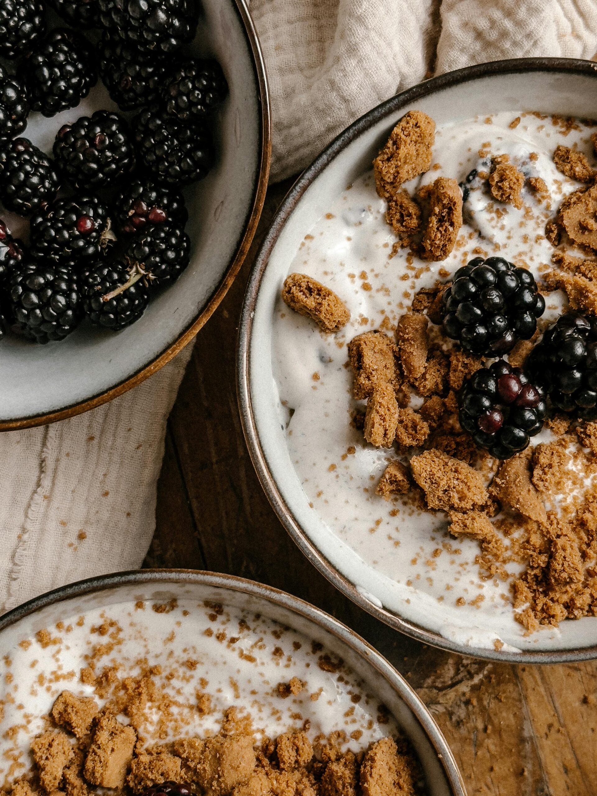 Close overhead view of homemade cream of wheat topped with fresh berries and brown sugar in rustic serving bowls.