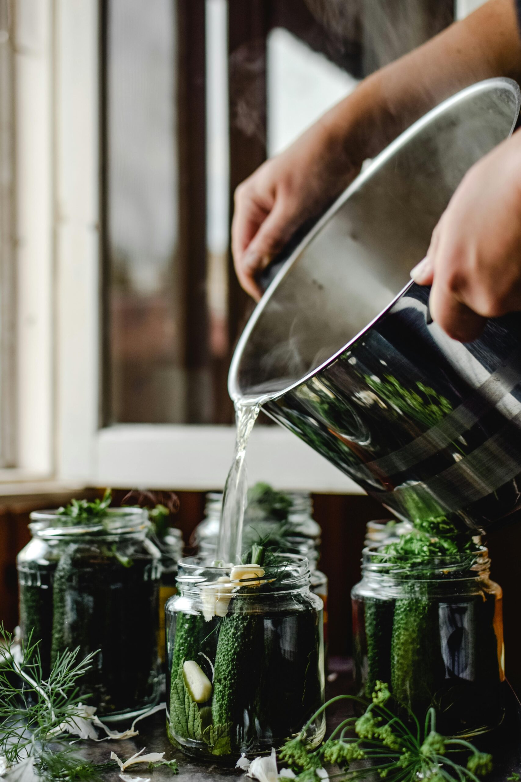 Brine poured into salt brine fermented pickles in a homestead kitchen