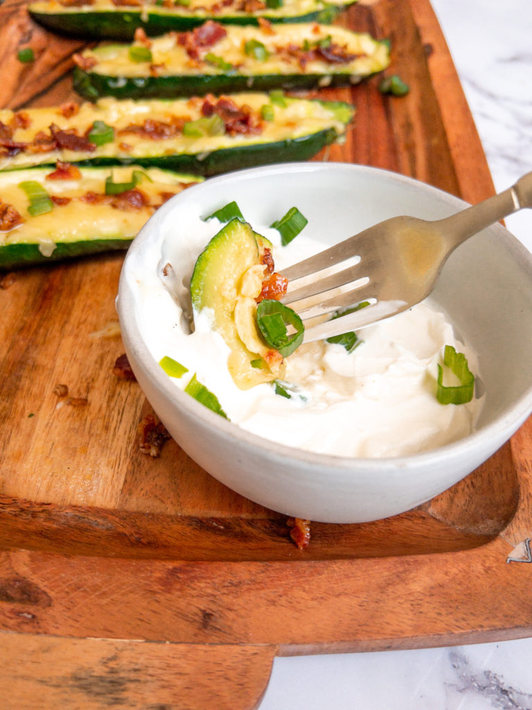 Dipping loaded zucchini boat pieces in sour cream