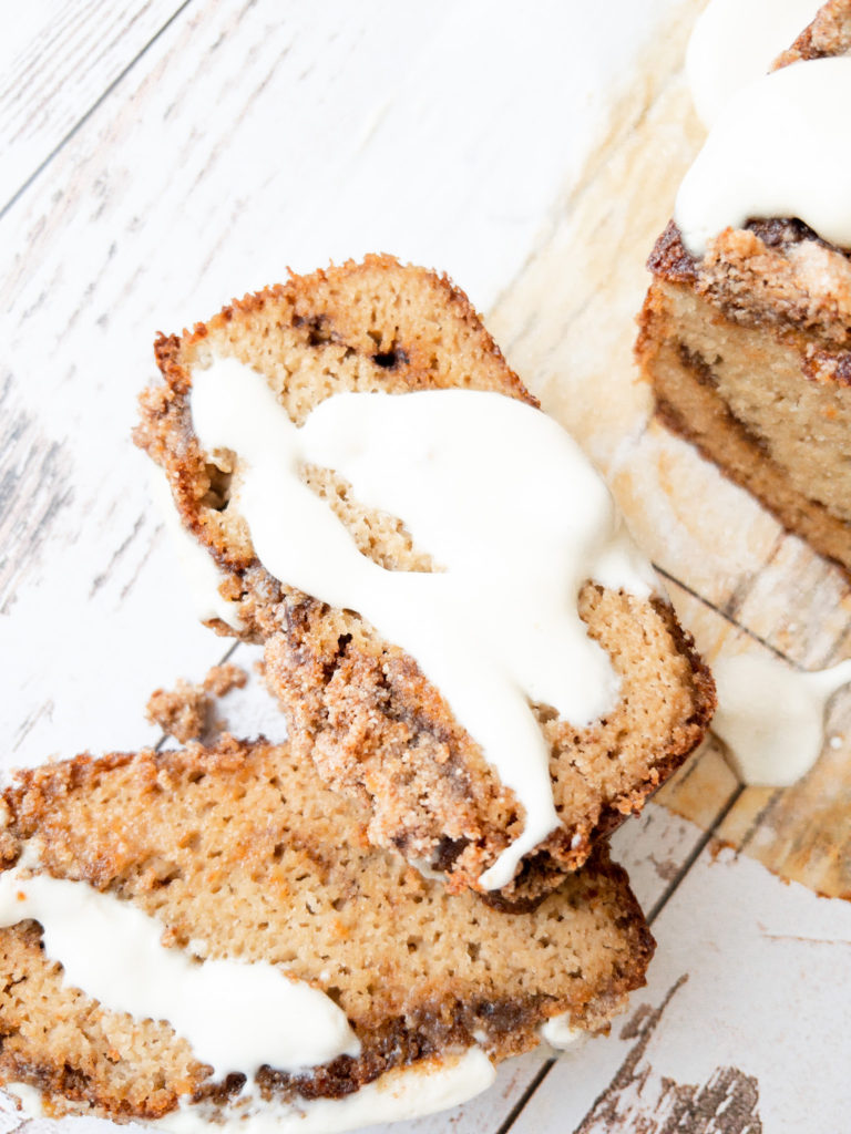 A slice of gluten free cinnamon roll bread with cream cheese glaze.