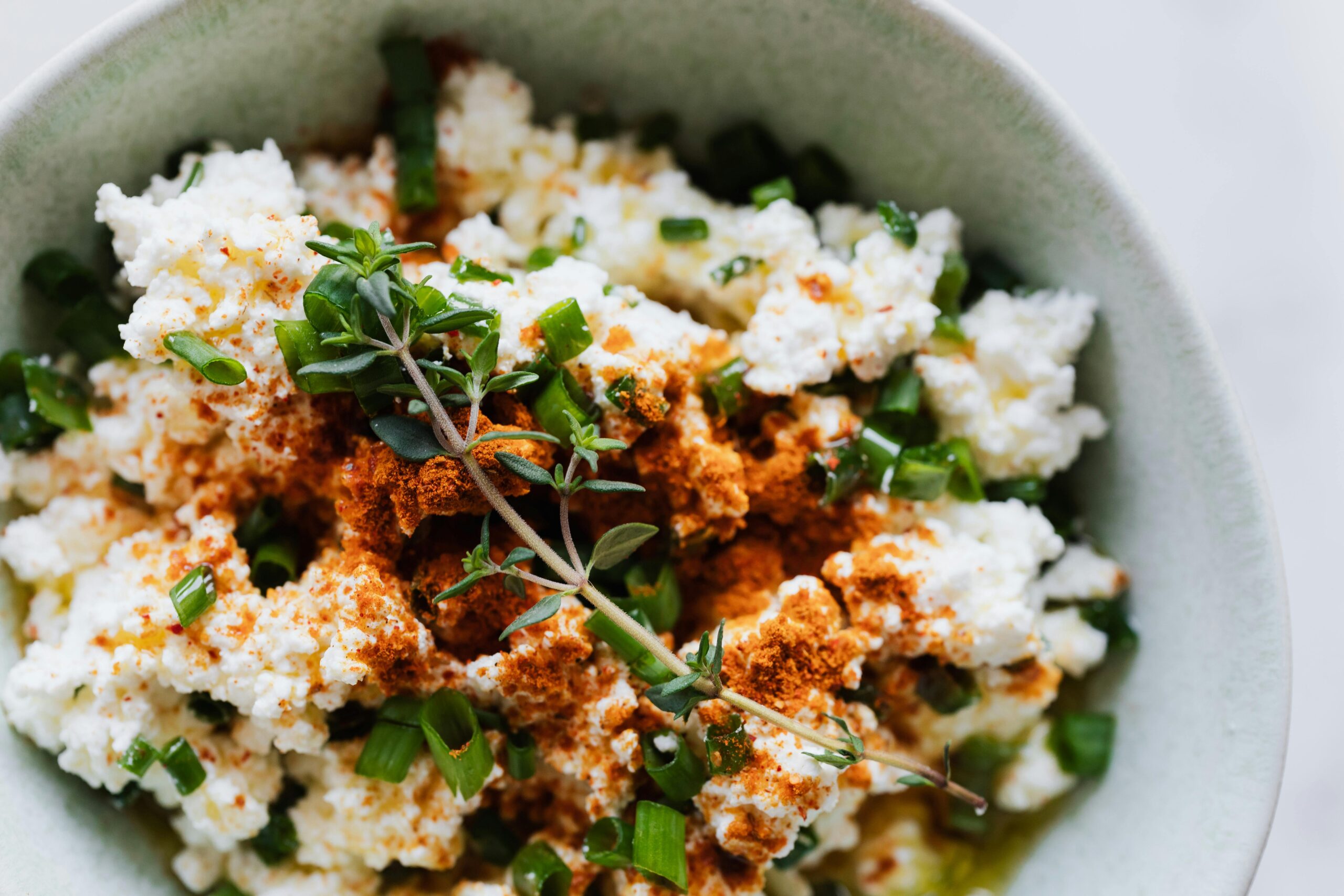 Farmers cheese in a bowl with herbs in a farmers cheese recipe showing how to make farmers cheese