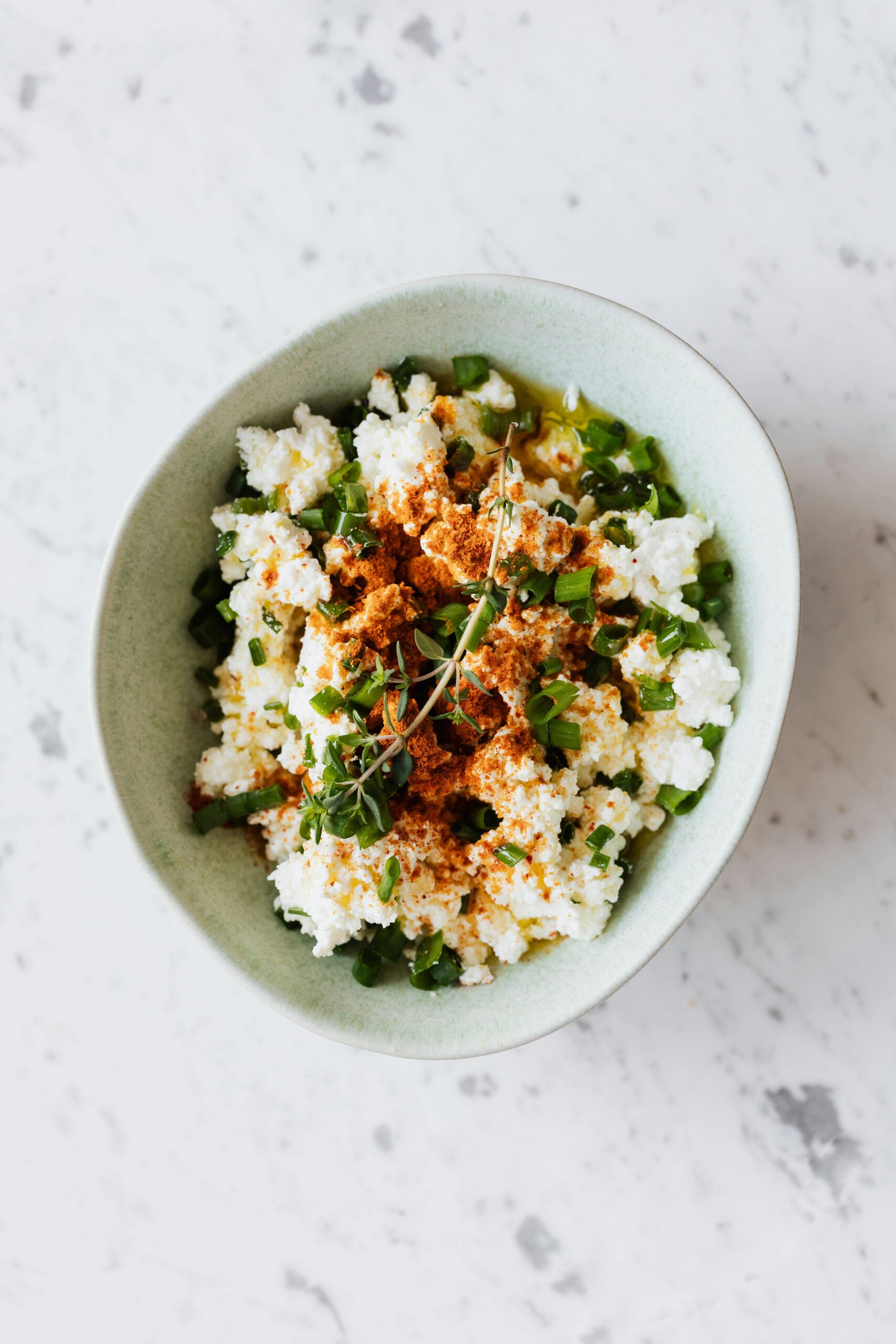 Farmers cheese in a bowl with herbs in a homemade cheese recipe and an easy cheese recipe